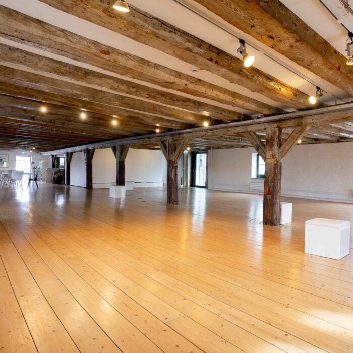 Galerie-Etage des Vegesacker Geschichtenhauses mit markanten Holzdeckenbalken und hellem Holzdielenboden, vorbereitet für verschiedene Ausstellungen.